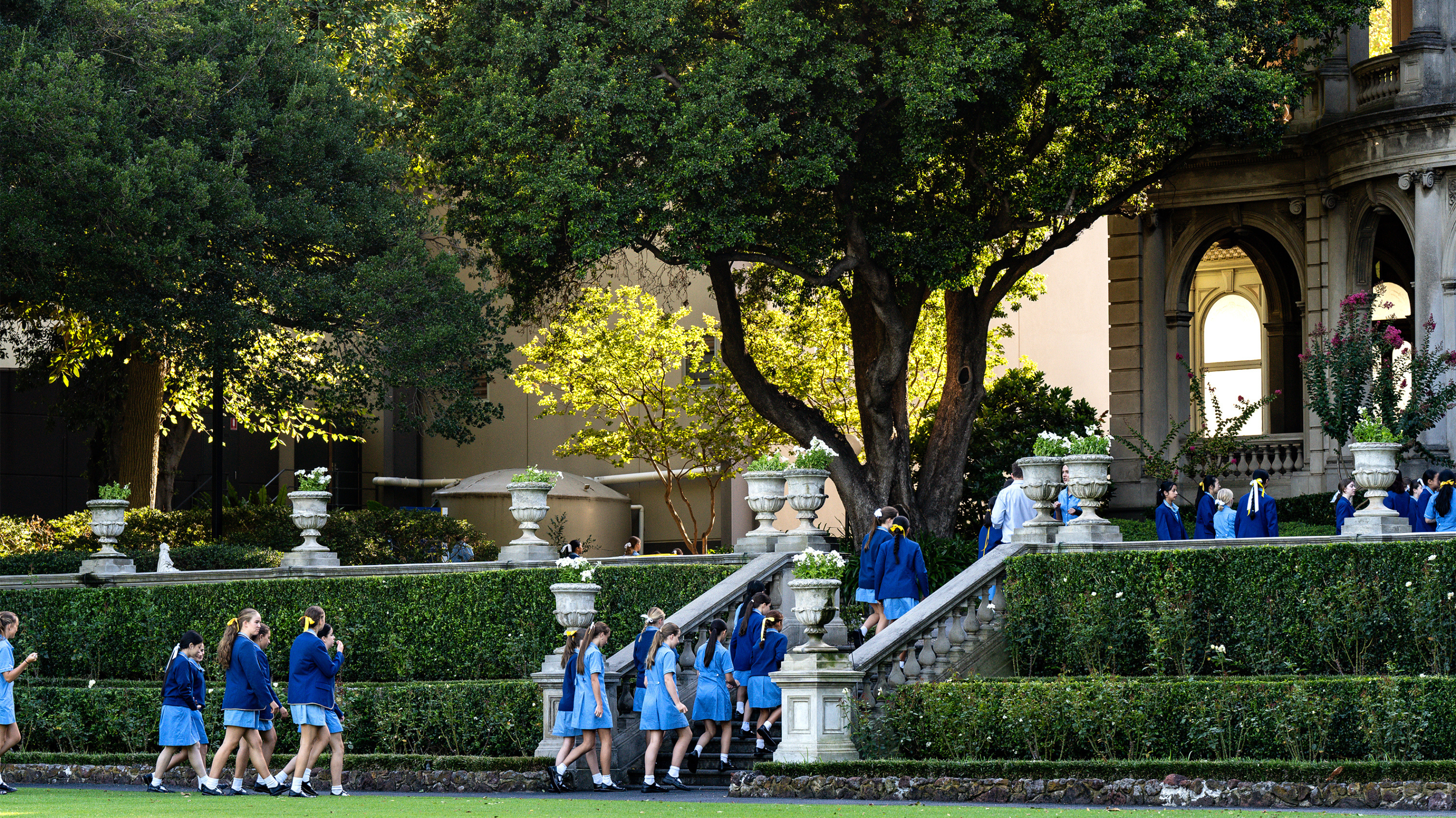 A group of Loreto Toorak students in uniform walking across the green school field